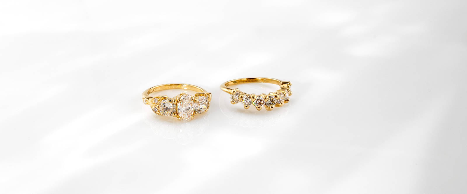 Yellow-gold oval three-stone engagement ring with curved diamond wedding band on a white background